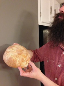 Classic Frugal Weirdo: Mr. FW holding bread he baked, next to the wall he built and the cabinets we painted, while wearing a shirt from the trash.