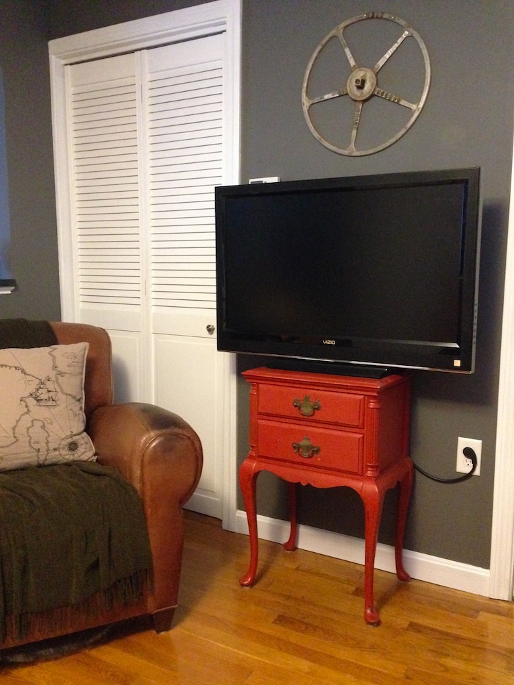 Our TV, chilling on its Craiglist stand, next to a Craigslist chair, below a Craigslist valve wheel-turned-wall-art